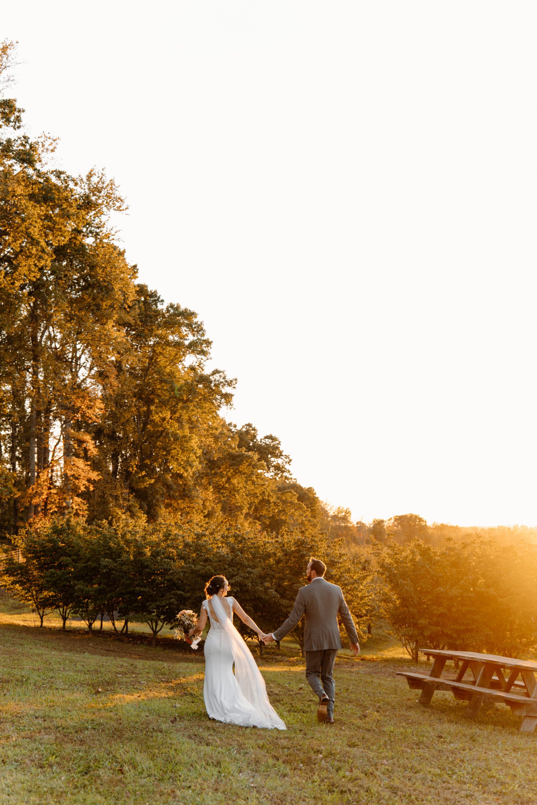 bride and groom running through the orchard on wedding day at the market at grelen
