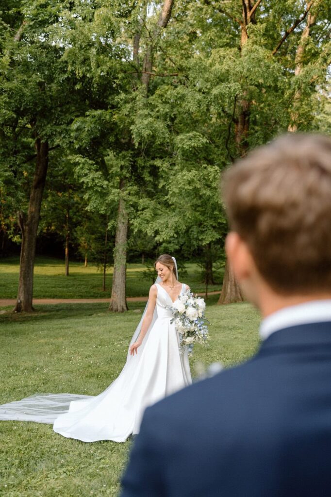Romantic shot of the groom watching the bride pose on the Belle Meade lawn