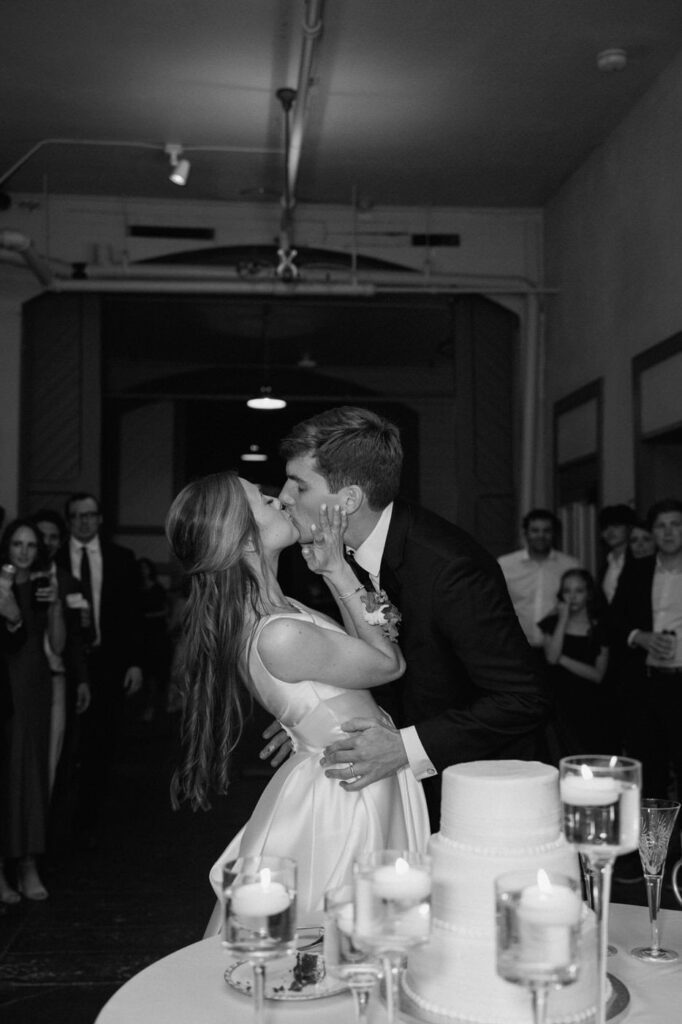 couple kissing during cake cutting at belle meade wedding