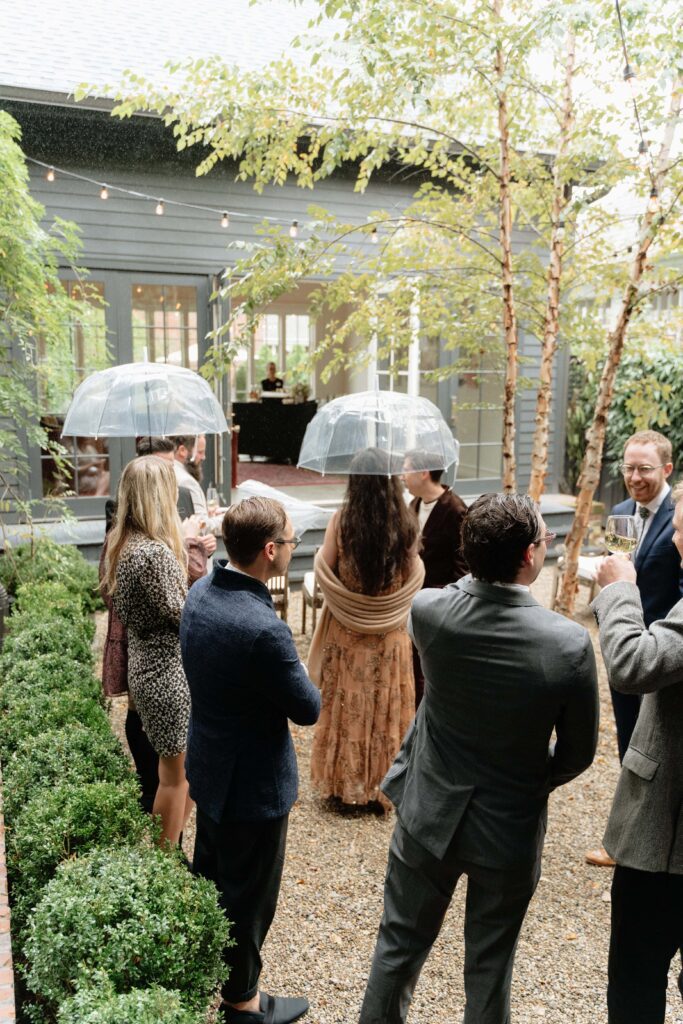 Wedding guests hugging and greeting each other in the rain
