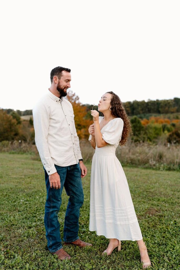 Candid moment with a couple blowing on a dandelion at a winery in Virginia