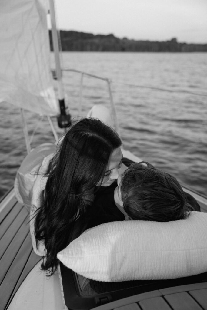 Couple laying together as the boat glides across Percy Priest Lake in Nashville during sunset sailboat session
