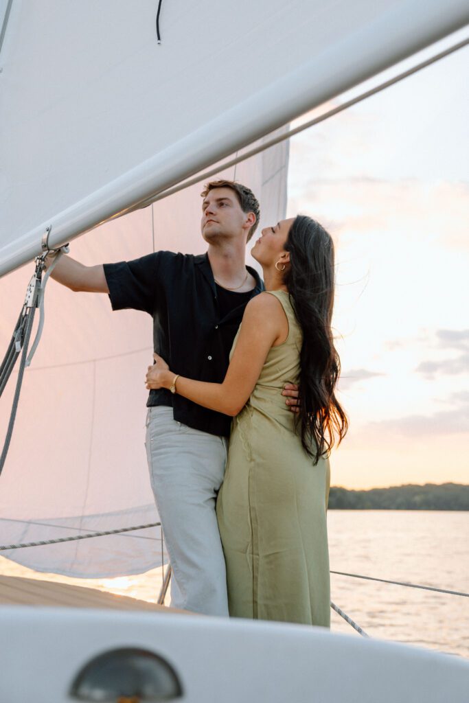 Wind catching the sail while the couple stands beneath it on Percy Priest during a sunset sailboat session