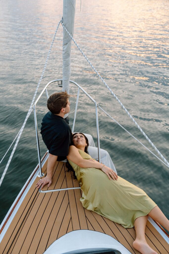 Couple laying together at the front of the sailboat during sunset