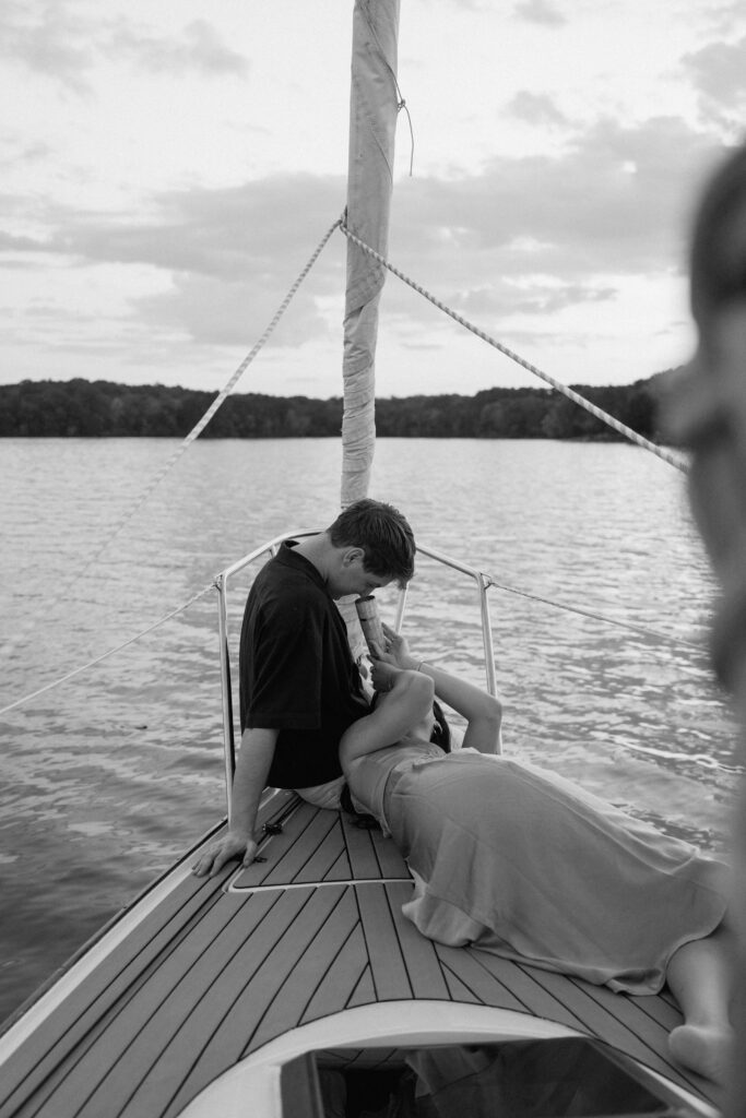Couple having fun at the front of the sailboat during golden hour
