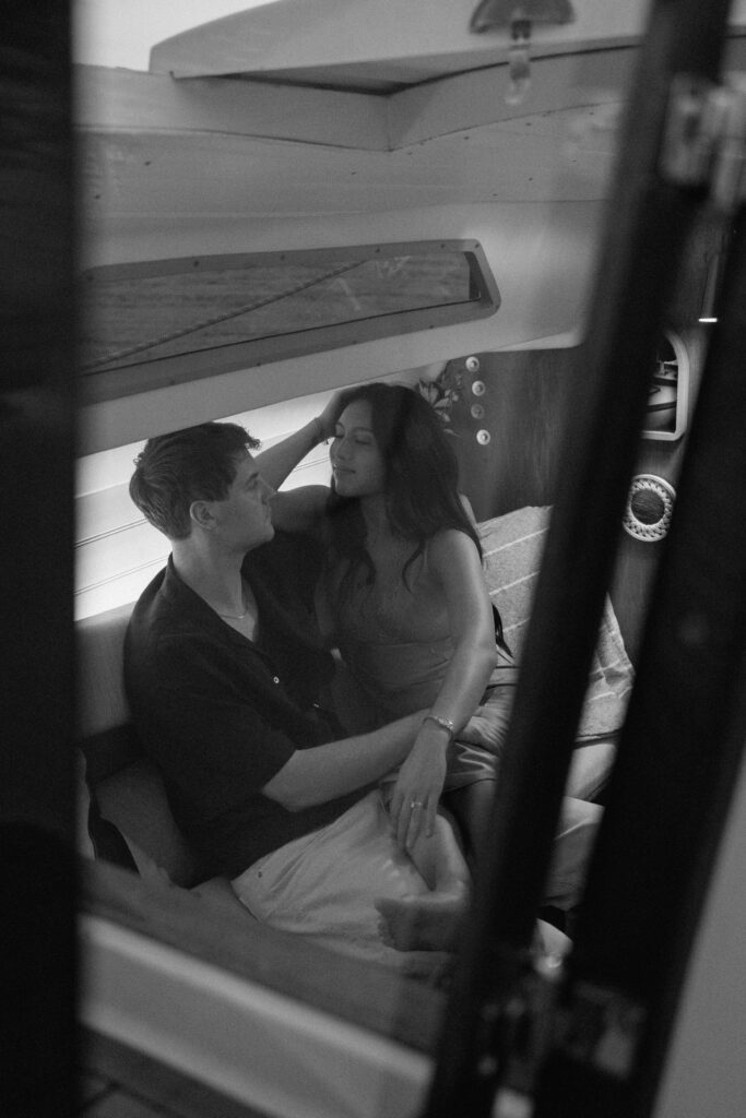Couple leaning into each other inside the sailboat during sunset
