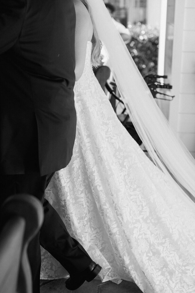 black and white image of the brides dress and her fathers suit as they walk into the chapel