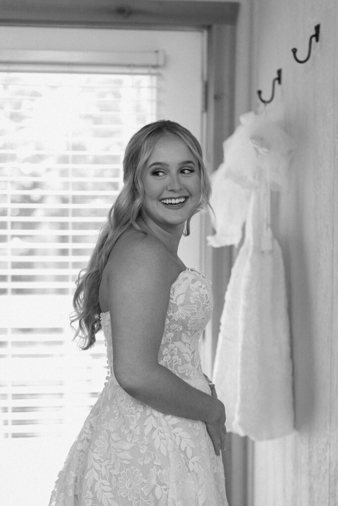 bride smiling back at her bridesmaids after getting in her dress