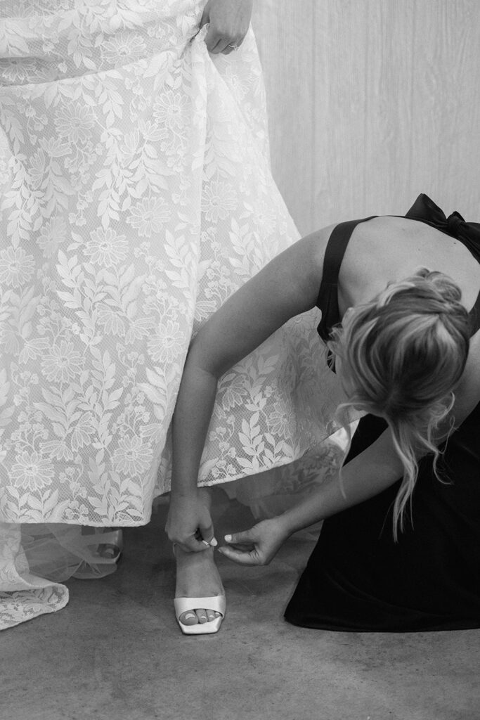 maid of honor putting shoes on the bride at the chapel at firefly lane