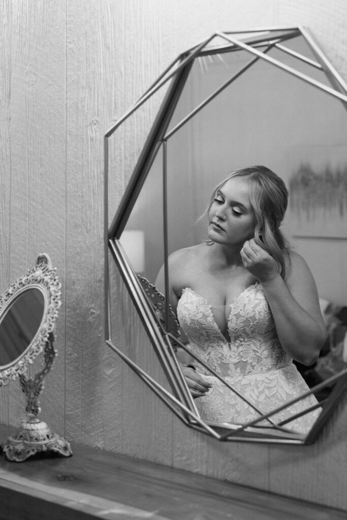 black and white image of bride putting on her earrings at the chapel