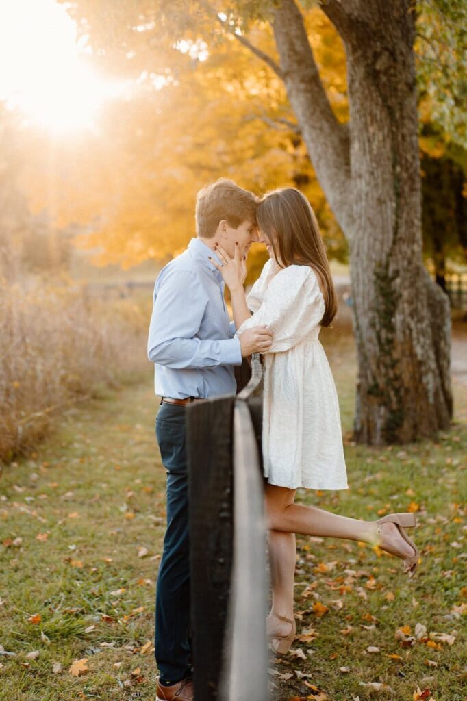 couple about to kiss over the fence at sunset during engagement session in nashville