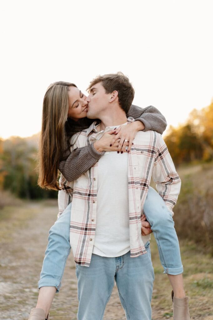 couple having fun with piggy back rides during fall engagement session in nashville