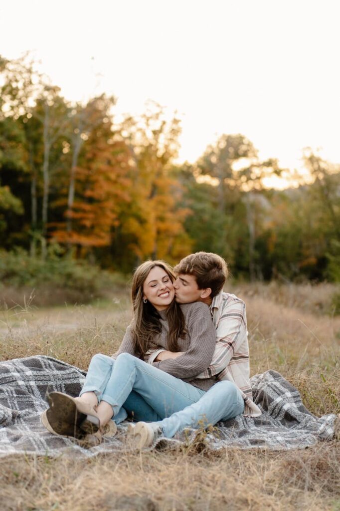 couple sharing a kiss on the cheek and sitting during their engagement session in nashville
