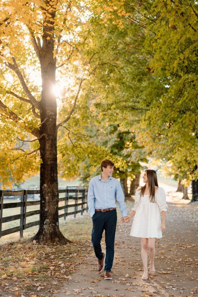 couple holding hands and walking down a path at smith park during fall engagement session in nashville