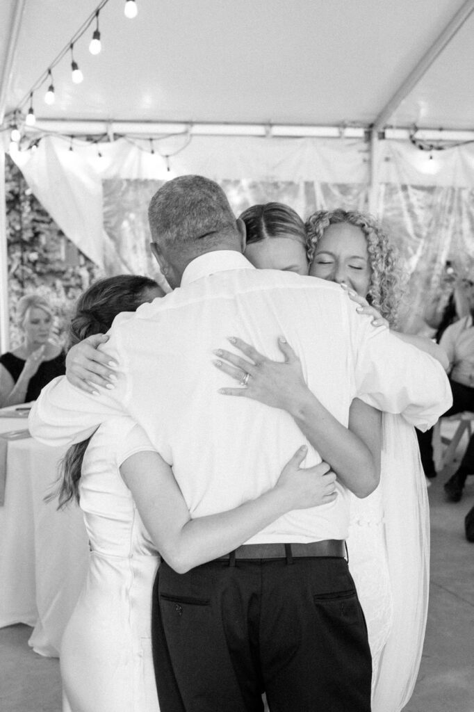 candid moment of father hugging daughters during wedding reception in tennessee
