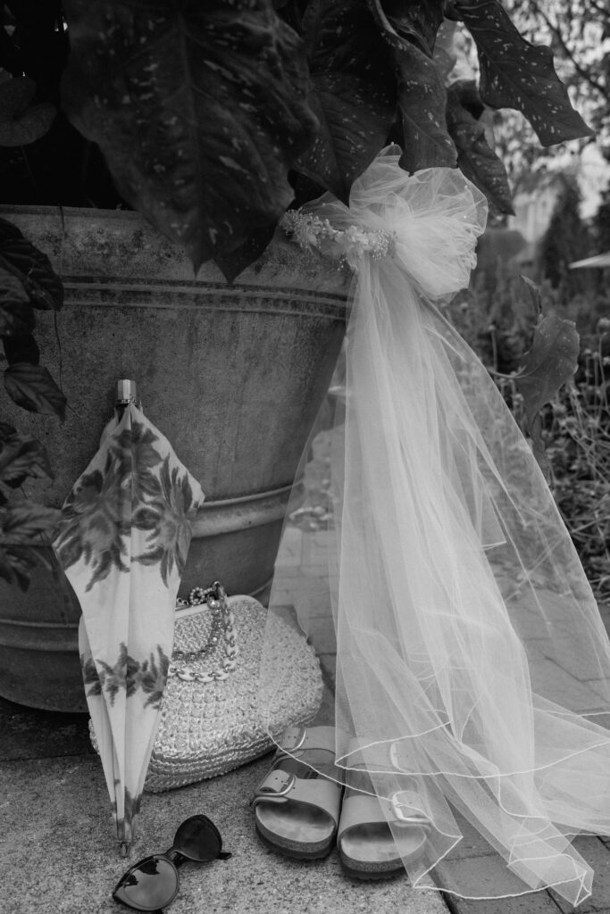 detail photo in black and white of bride's veil, shoes, and parasol 