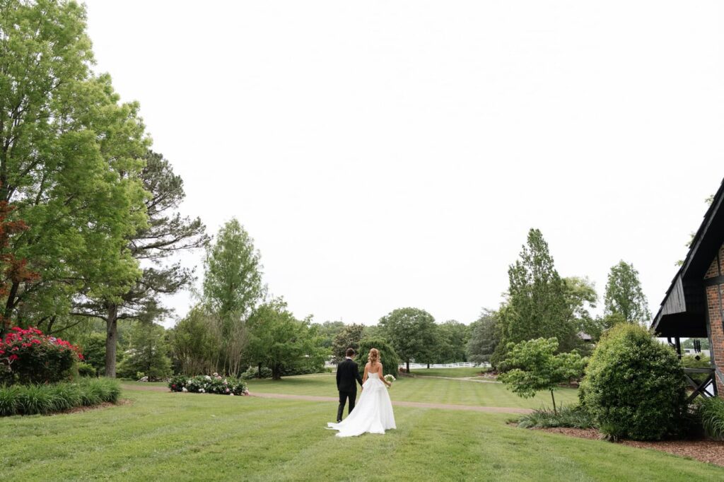 couple walking through an open field after considering how to find the right nashville tennessee wedding photographer