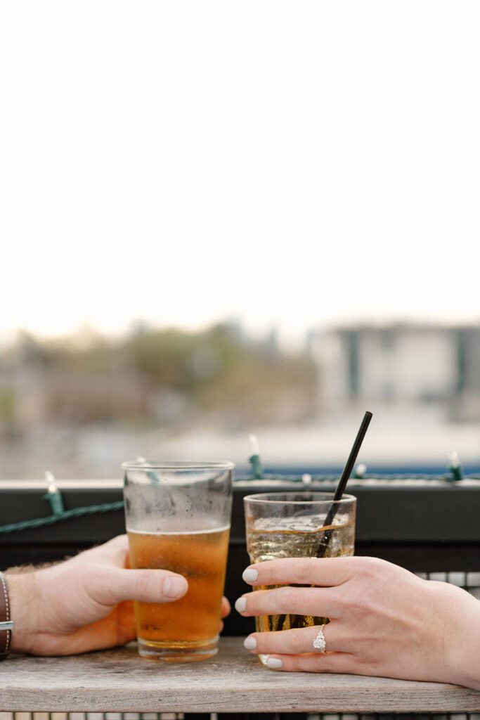couple holding their drinks during engagement session in east nashville