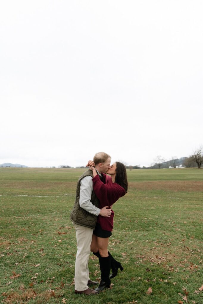newly engaged couple kissing in a field in franklin tennessee