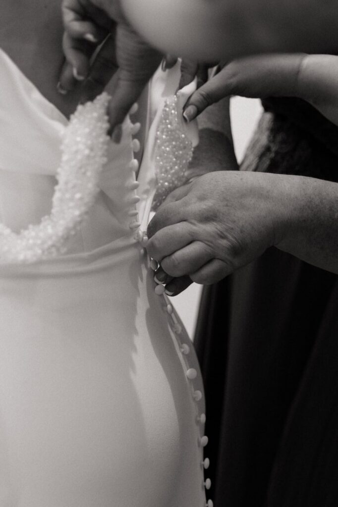 mother of the bride zipping up her dress on wedding day