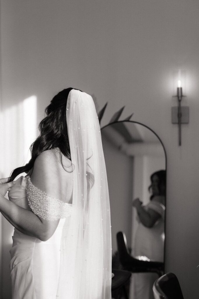 bride looking at herself in the mirror while getting ready on her wedding day