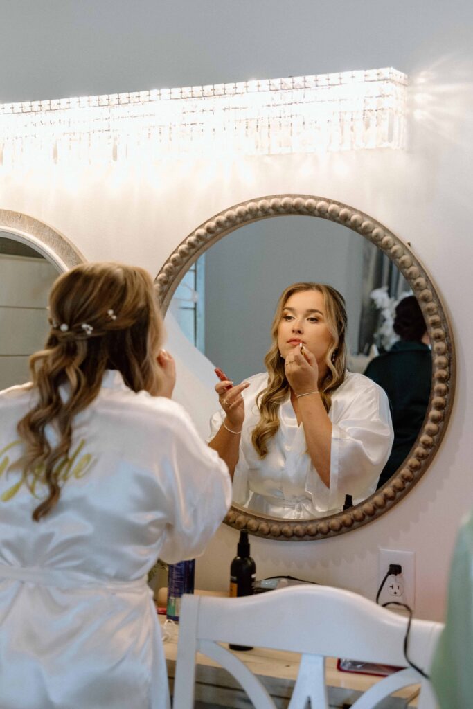 bride putting on makeup while getting ready on her wedding day in nashville