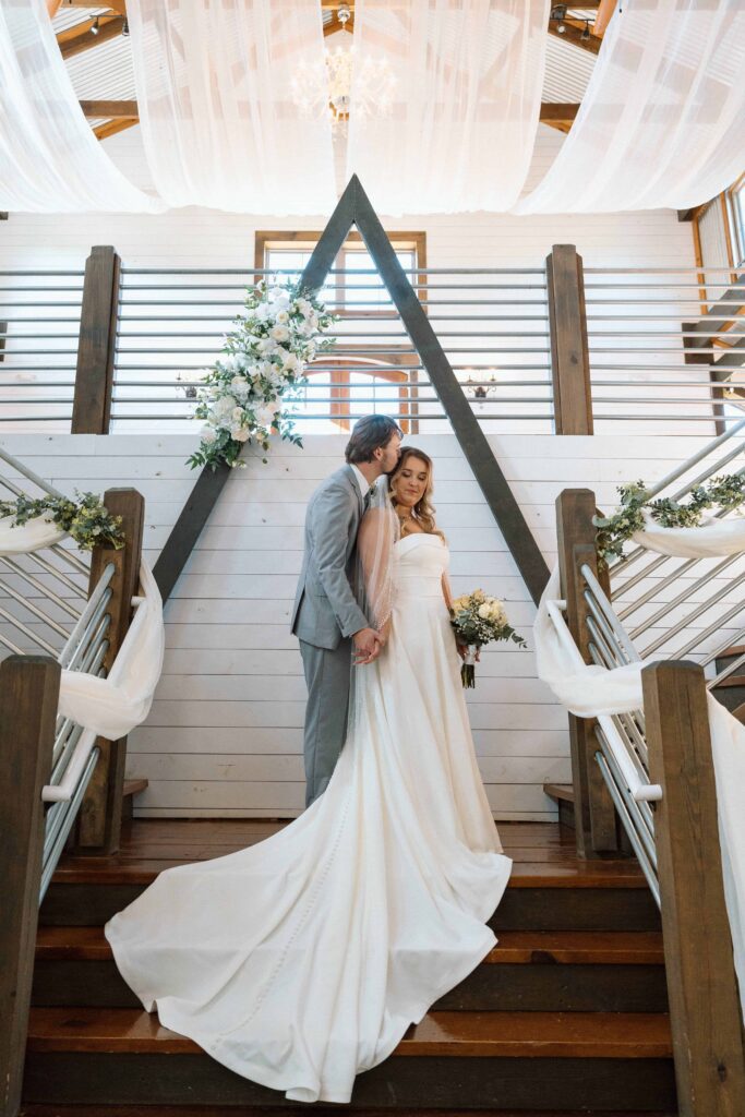 bride and groom standing on the stairs at the venue at fiddle dee farms on their wedding day in tennessee