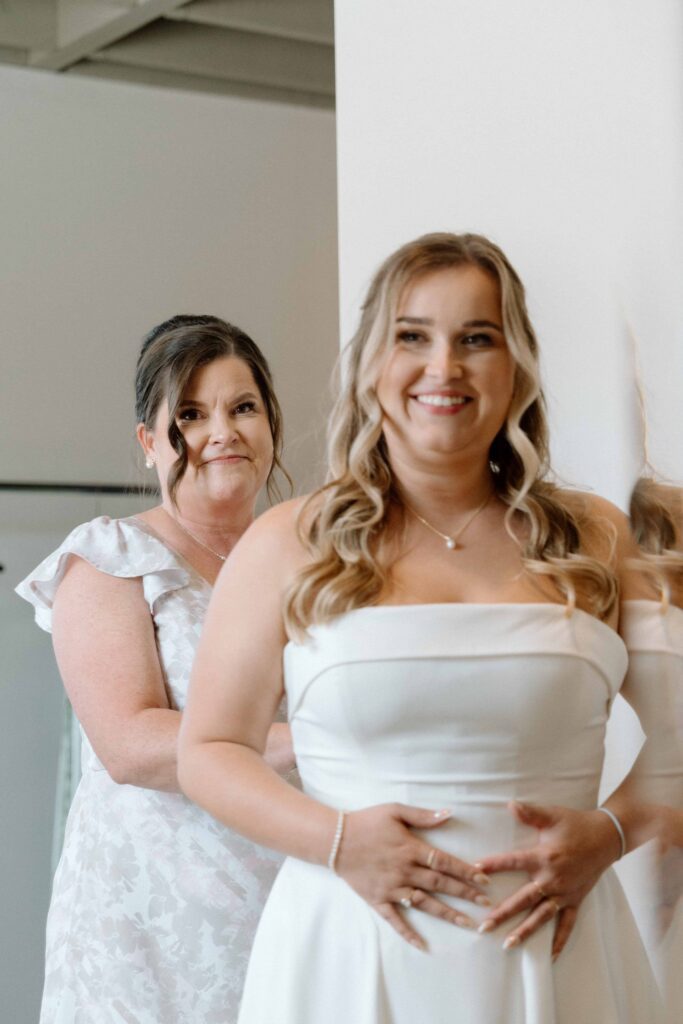 mother of the bride helping her into her dress