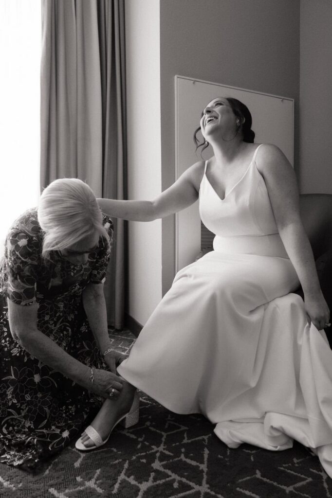 mother of the bride helping her put on her shoes for wedding day