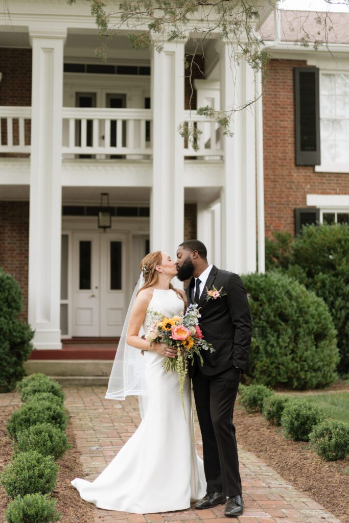 bride and groom kissing outside of historic house at cedarmont farm in franklin tennessee
