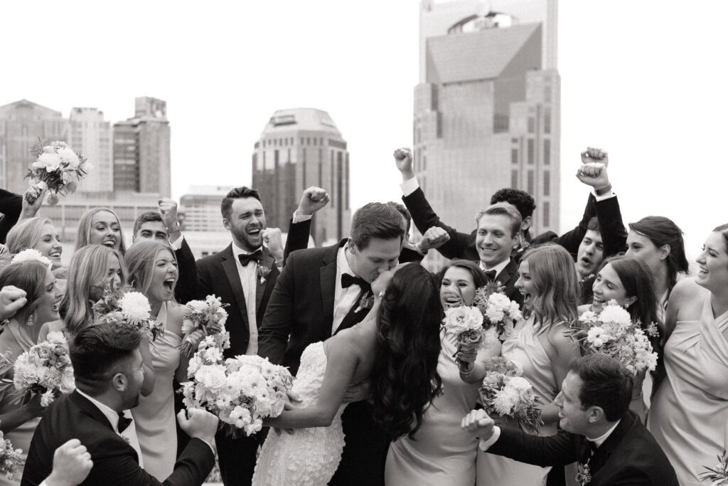 bridal party cheering in front of nashville skyline at the country music hall of fame