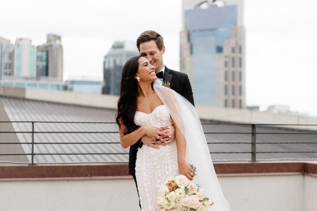 couple laughing candidly at country music hall of fame wedding in front of nashville skyline