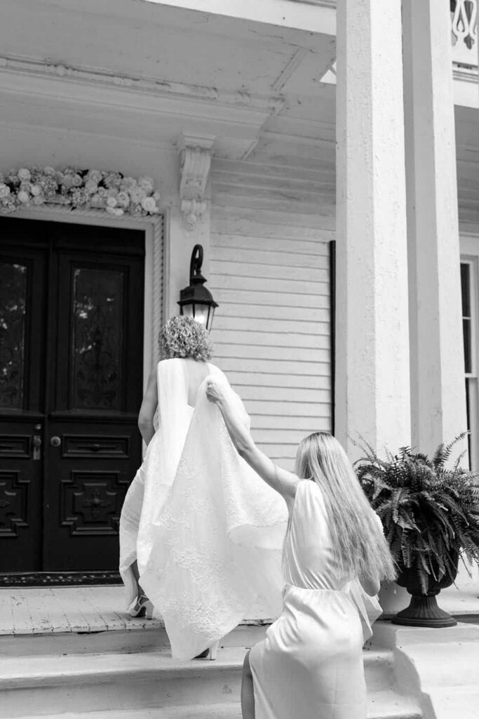 maid of honor carrying brides dress up the stairs of tennessee wedding venue