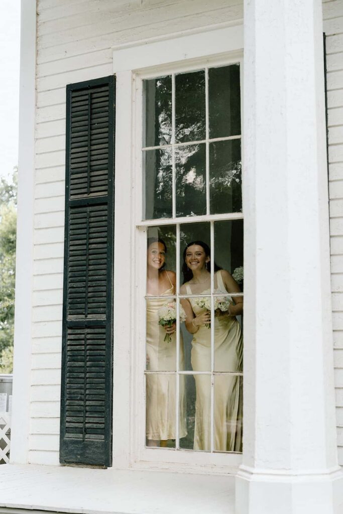 bridesmaids smiling through the window at tennessee wedding venue
