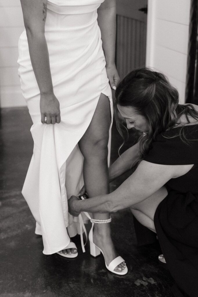 mother of the bride helping put on her shoes