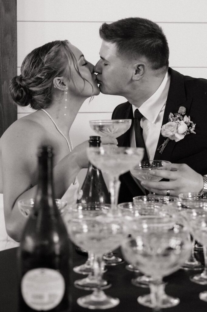 bride and groom kissing behind champagne tower
