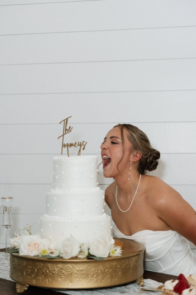 bride playfully biting into wedding cake