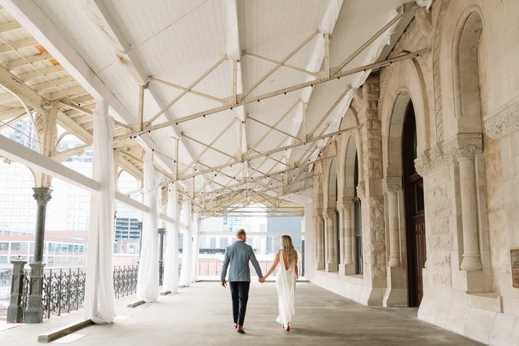 couple holding hands and walking outside of union station in nashville