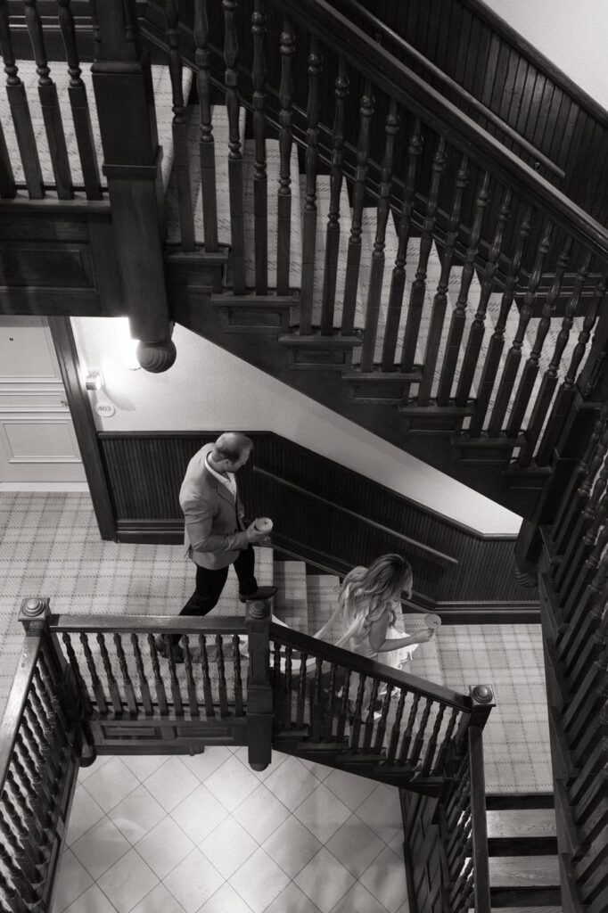 couple walking down the stairs at union station hotel carrying cocktails during engagement photos