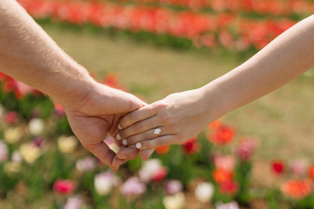 couple holding hands in front of tulips