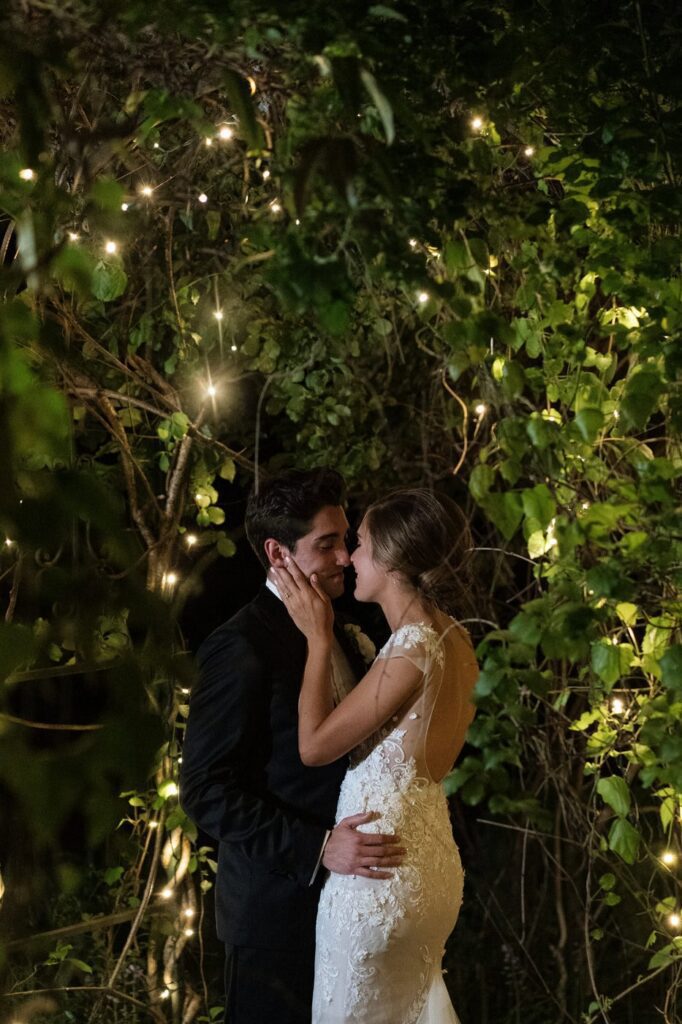 couple in the gardens under the string lights at riverwood mansion on their wedding day
