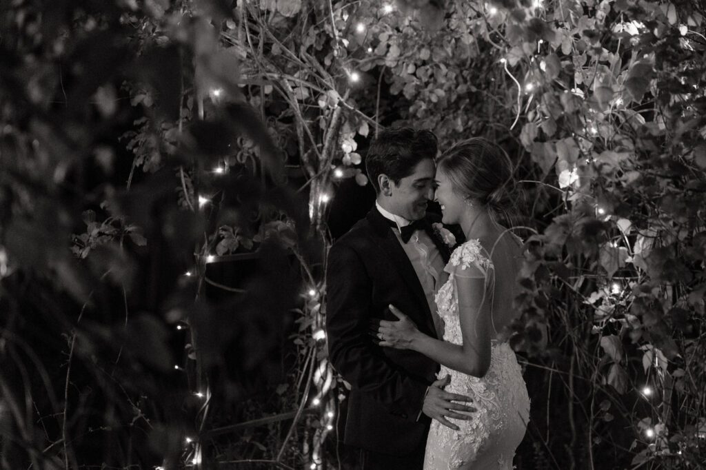 couple smiling in the gardens under the lights