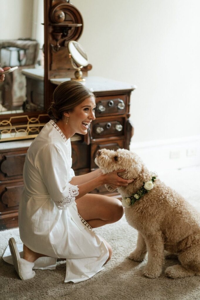 bride smiling and petting her dog in the bridal suite at riverwood