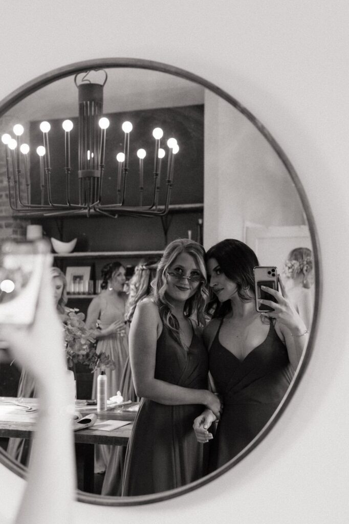 candid moment of bridesmaids taking a mirror selfie