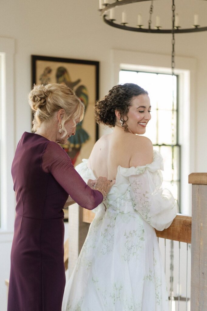 mother of the bride zipping up her dress on wedding day