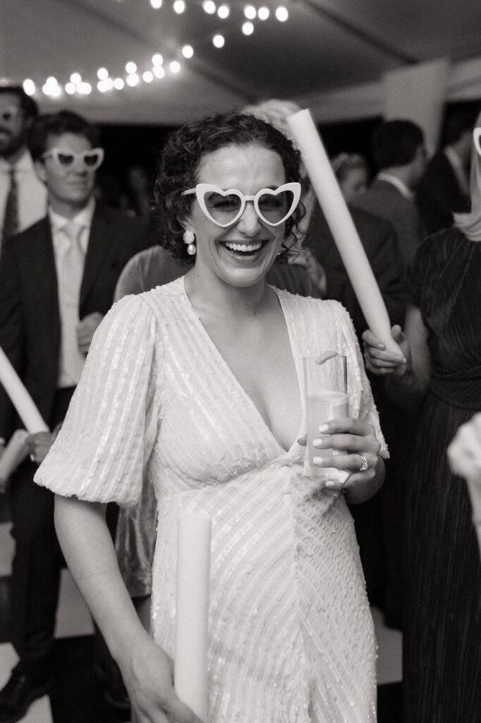 bride laughing wearing heart sunglasses and holding a cocktail