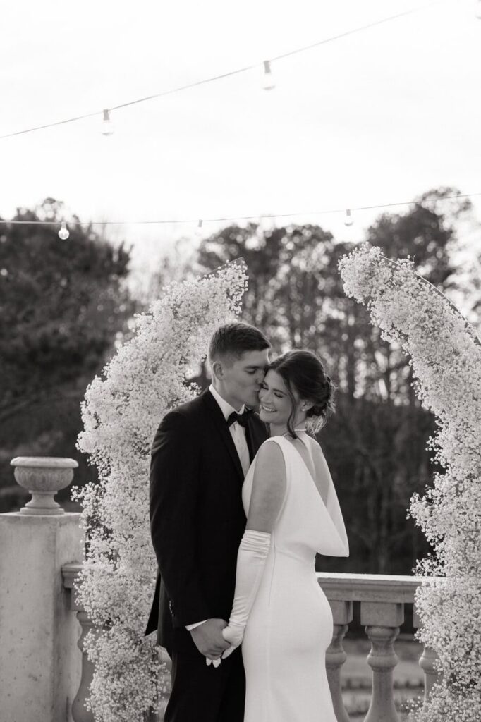 couple sharing a sweet moment under the floral arch at their dimora winter wedding 