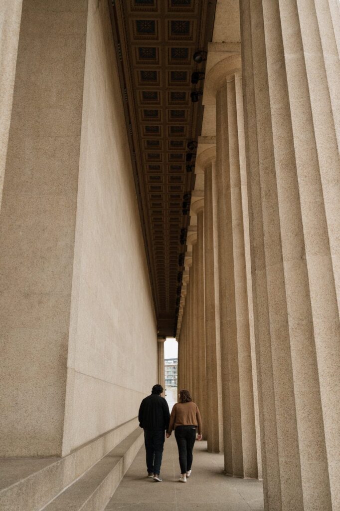 couple holding hands and walking through the parthenon
