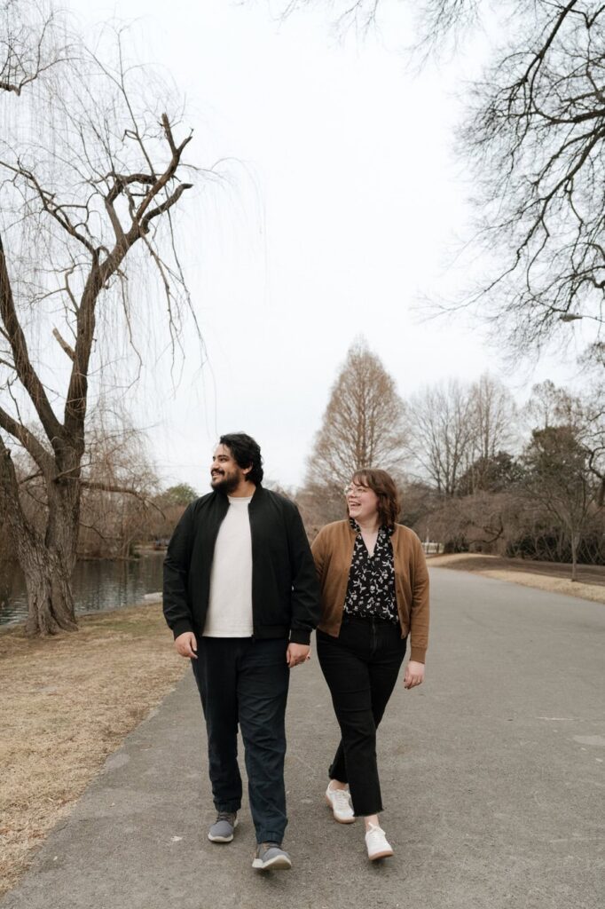 couple holding hands and walking at centennial park during engagement session in nashville