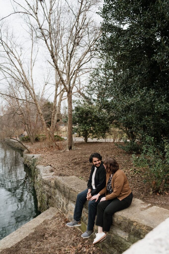 couple sitting on the stone wall at the park at nashville engagement session